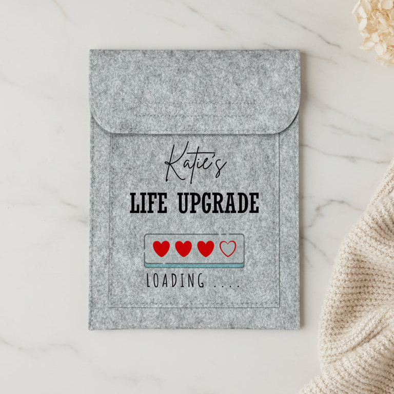 A personalized gray felt laptop sleeve with a flap, featuring the text 'Katie's LIFE UPGRADE' and a 'LOADING .